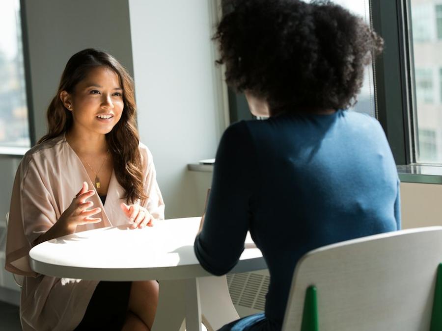 Bewerbungsgespräch an einem hellen Tisch, die Bewerberin lächelt